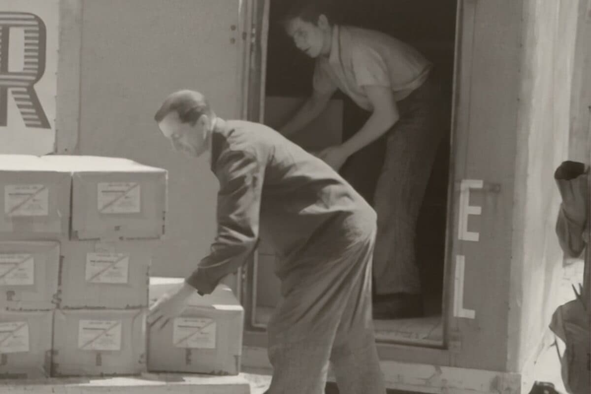Archival photograph of two movers loading boxes into a truck